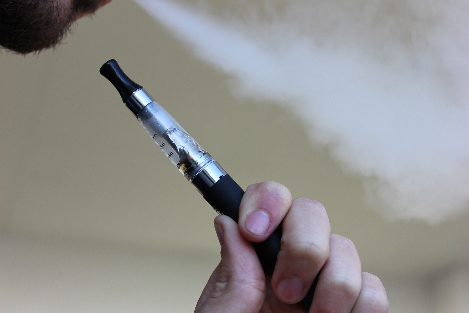 closeup hand holding vape pen with visible smokes