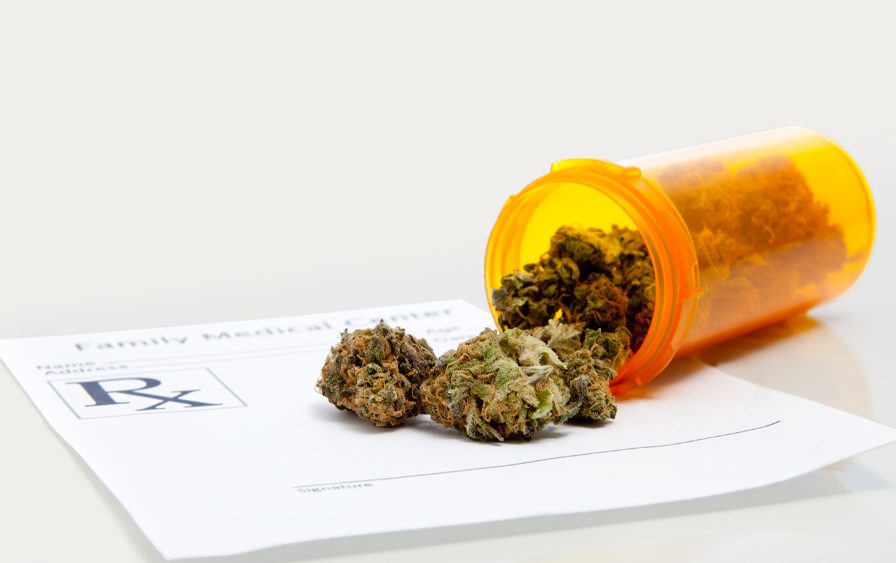 cannabis buds in a tumbled pill container on a prescription sheet