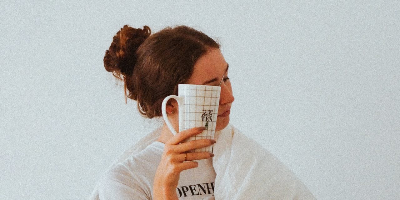 a woman holding a mug placing closer to her right eye