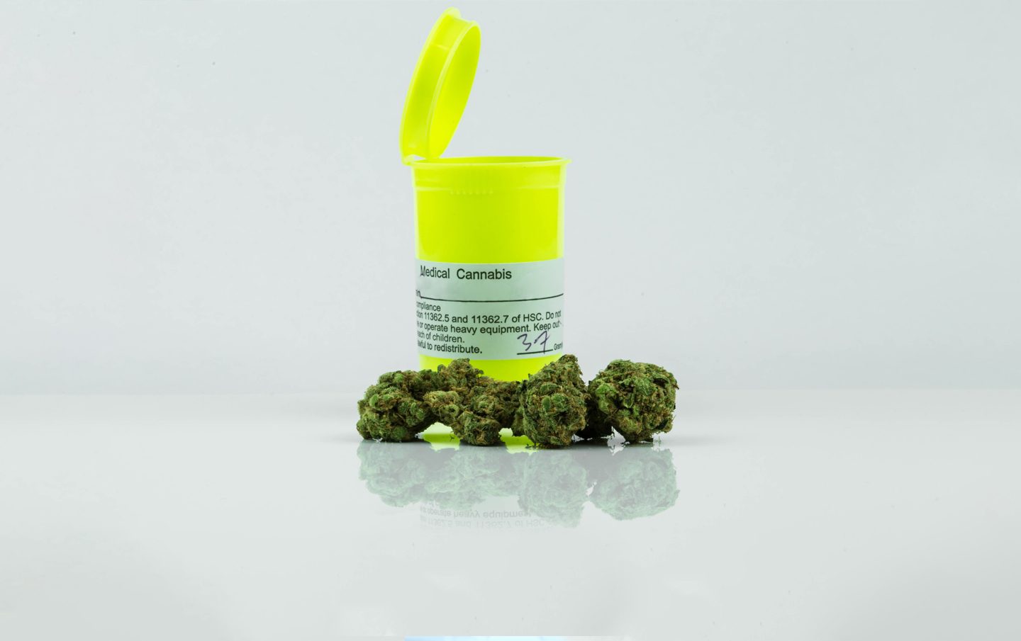 pill container with cannabis buds surrounding it