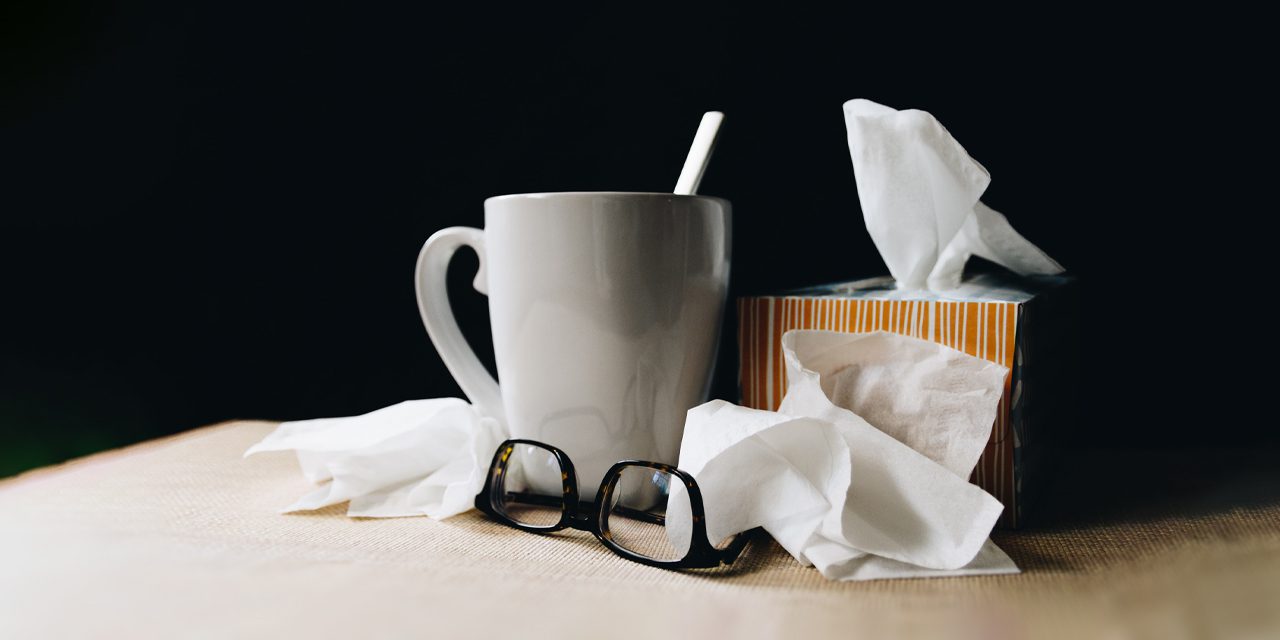 white mug beside a tissue box and eyeglasses
