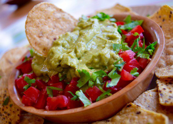 closeup of guacamole bowl with chips in and around it
