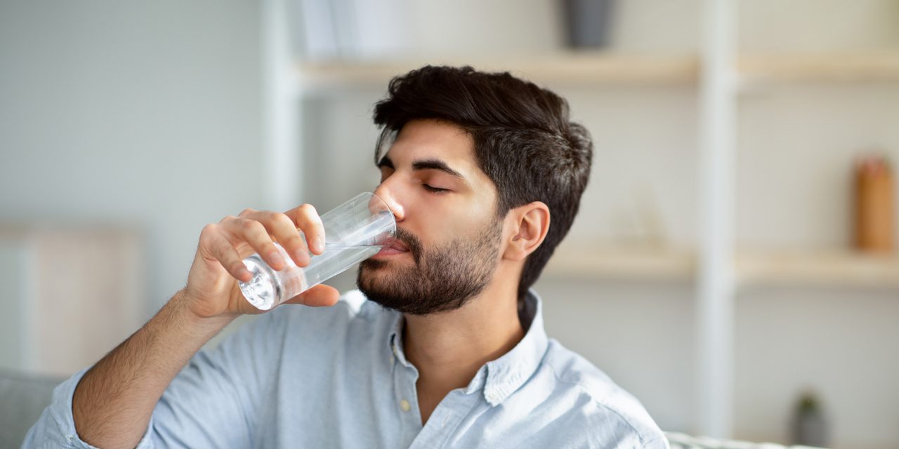 man drinking a glass of water