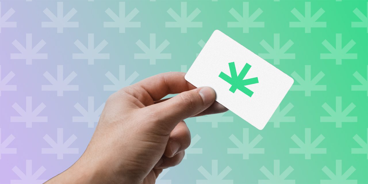 close-up of hand holding a card with the cannabis logo