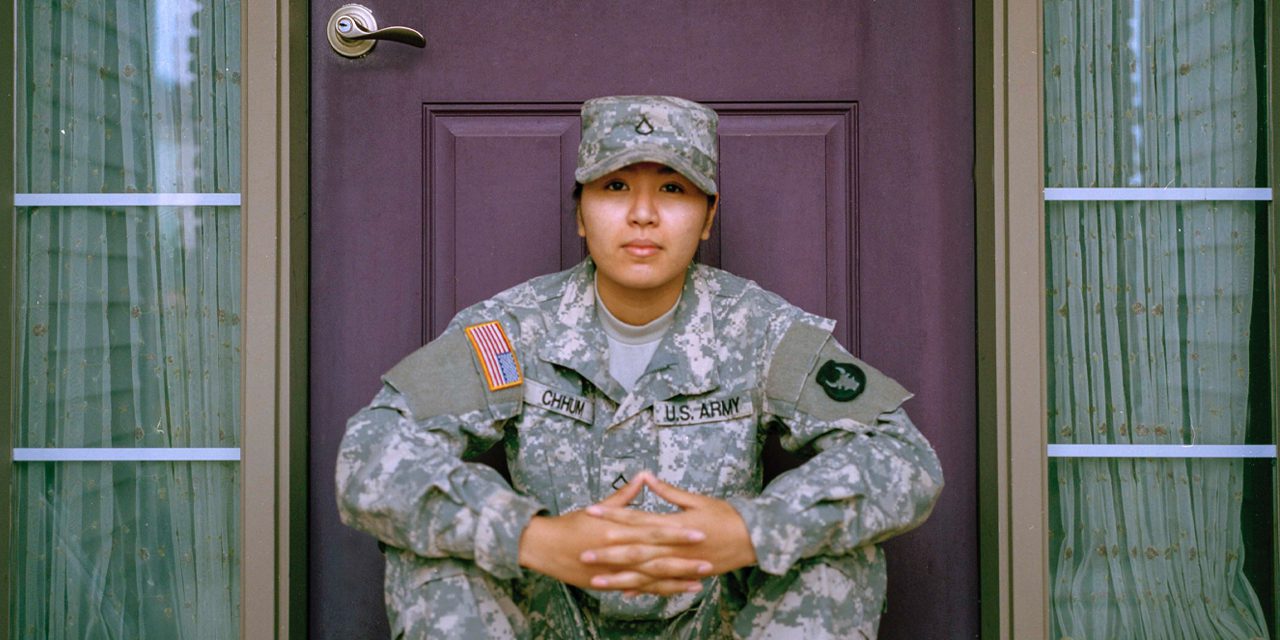 mujer con uniforme militar sentada frente a una puerta