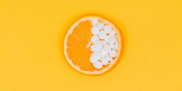 half sliced of orange and half part is tablets as vitamin C