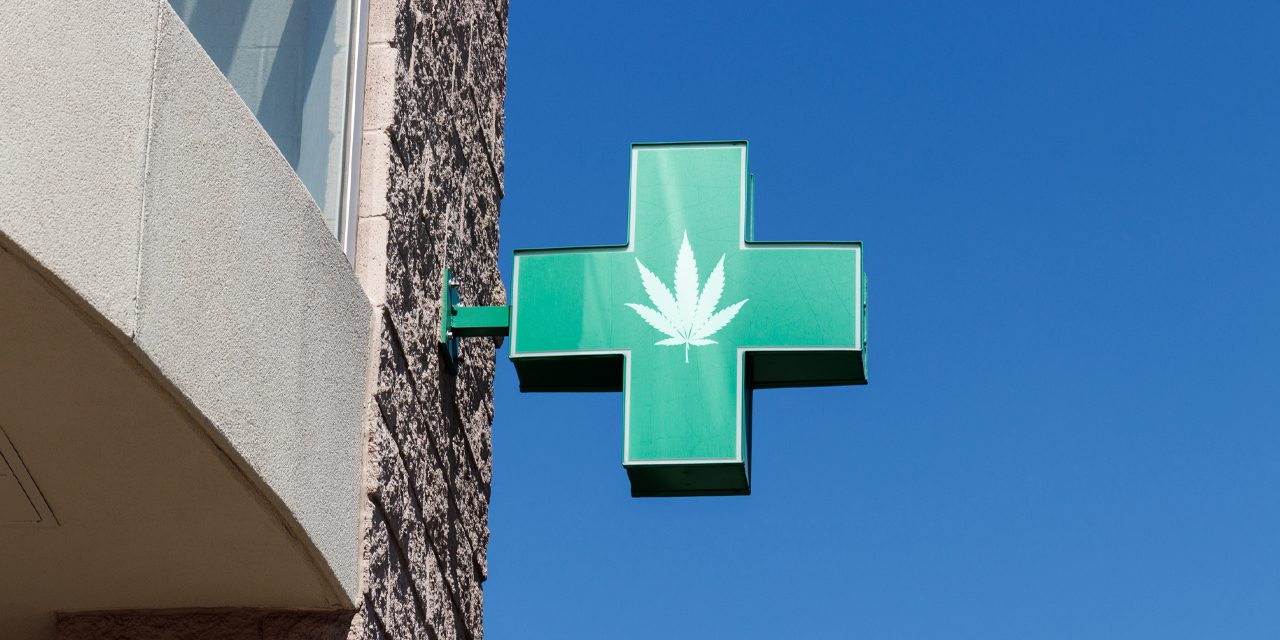 green cross shaped signage with image of marijuana leaf at the center