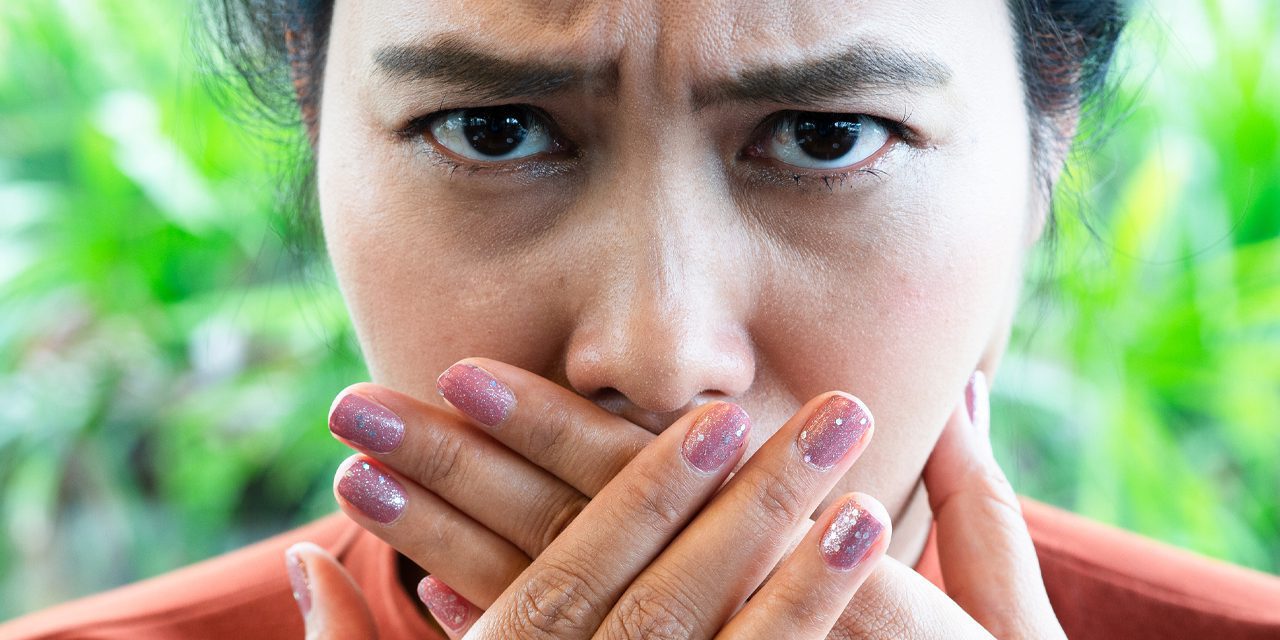 closeup woman's face covering her mouth with her two hands