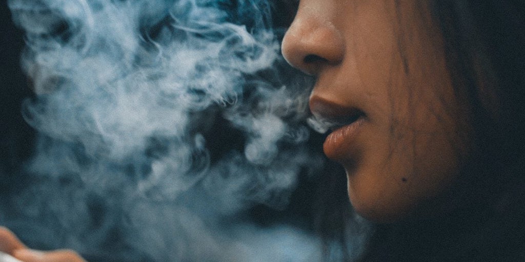 closeup woman's mouth blowing smoke