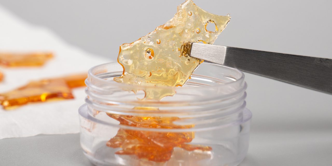 golden cannabis wax pieces shatter resin in a clear small container