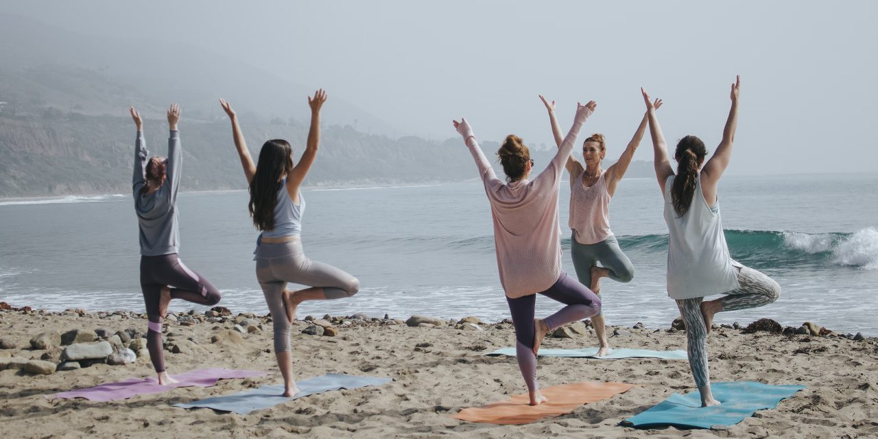 women doing yoga in the seashore