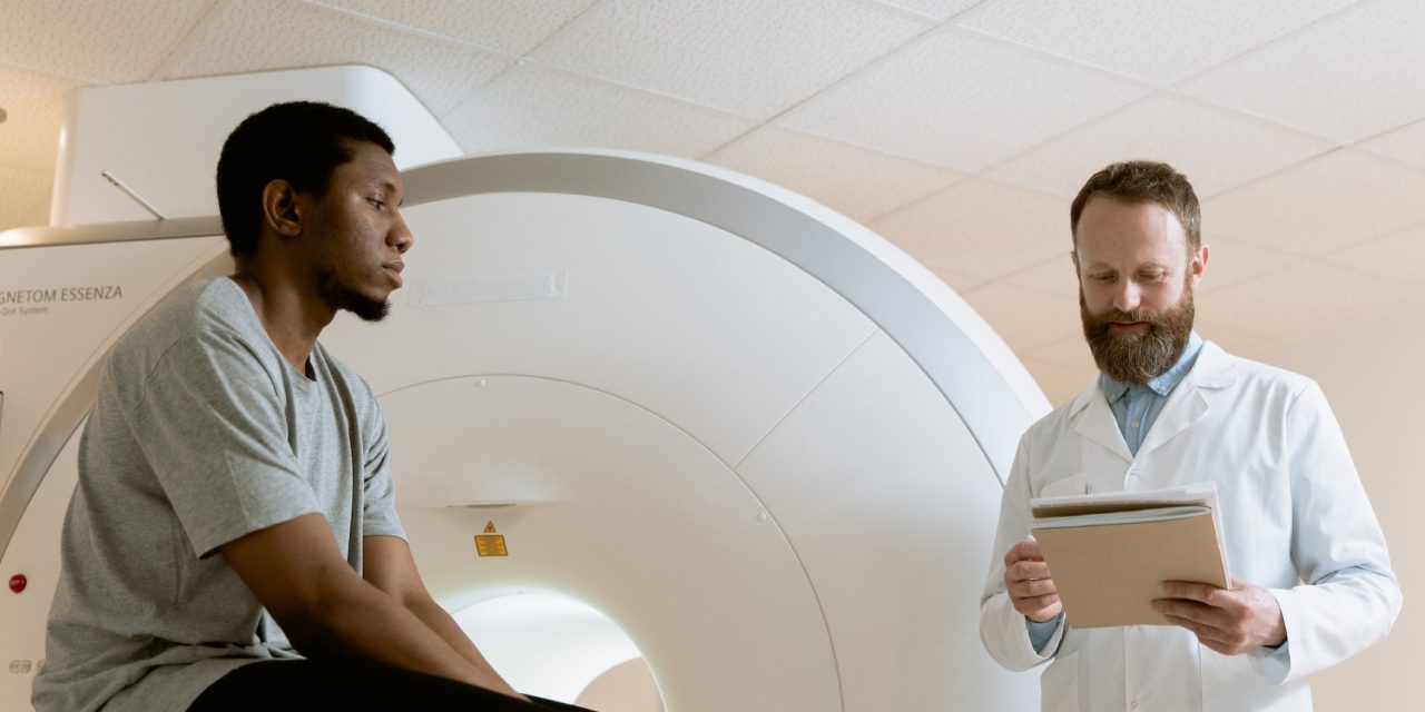 a doctor examining/explaining details to his patient beside the medical imaging equipment