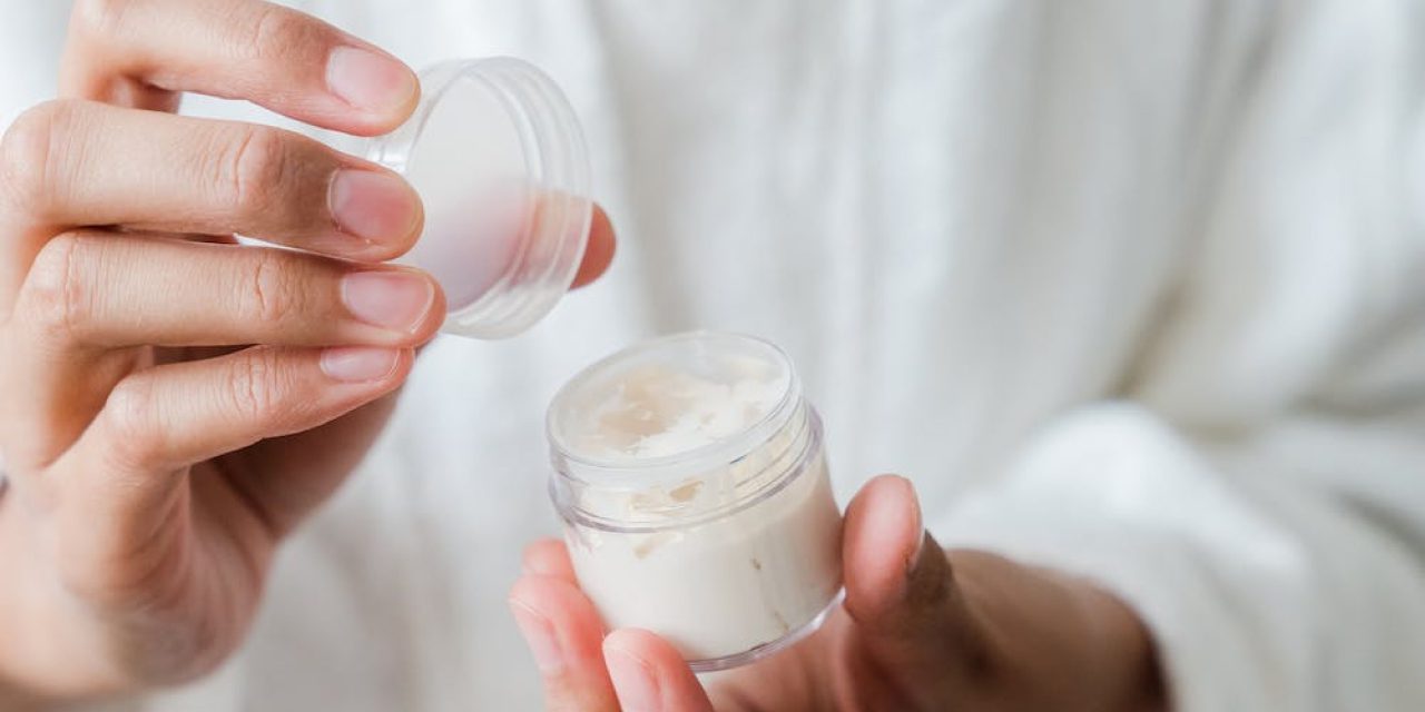 closeup of woman's hands holding a container with cream